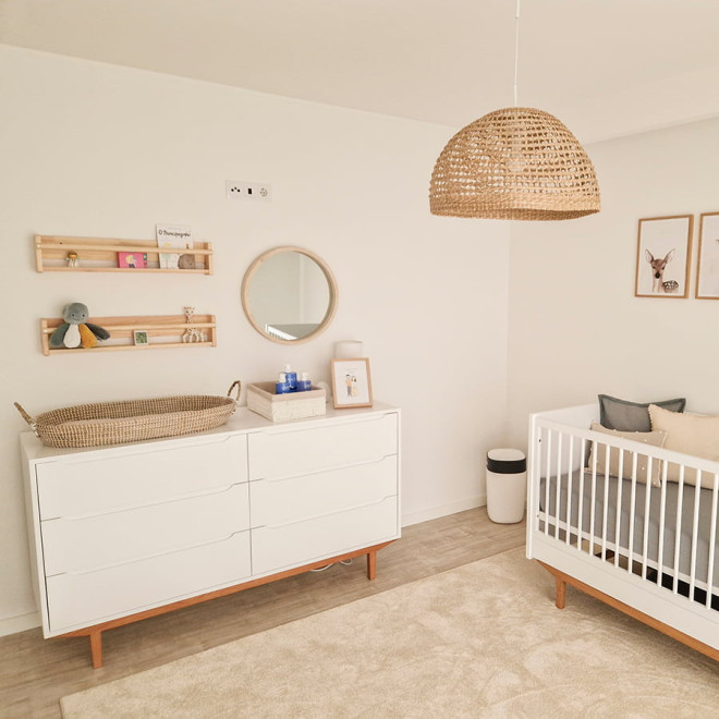 Weiße Babykommode mit Naturolzsockel und 6 Schubladen in einem dekorierten Kinderzimmer.